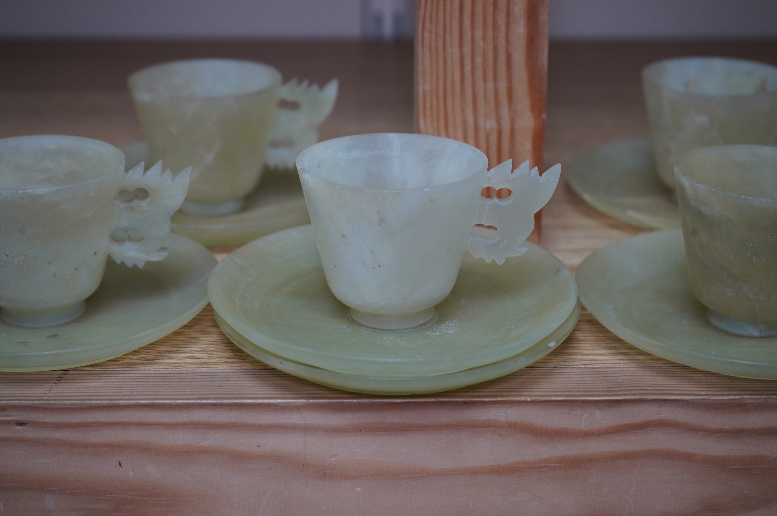 A set of seven Chinese bowenite jade cups and eight saucers, 11cm in diameter. Condition - fair to good